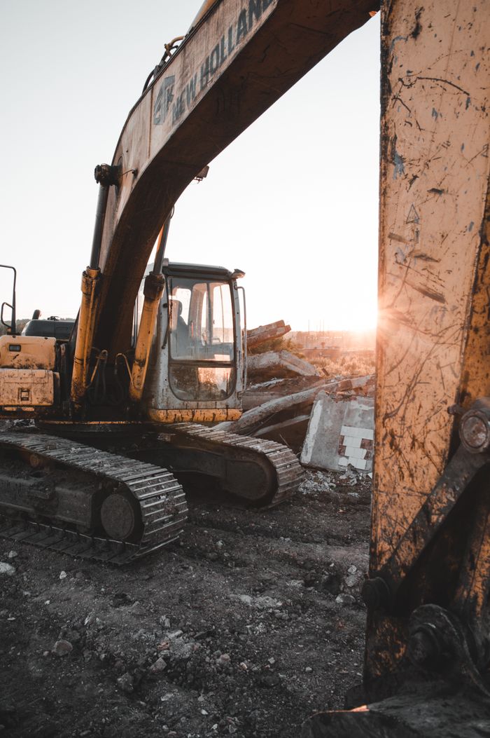 Contact 1 Heavy machinery at a construction site at sunset, showcasing industrial strength and raw power.