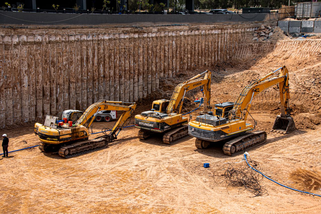 Three excavators working at a construction site for land excavation.