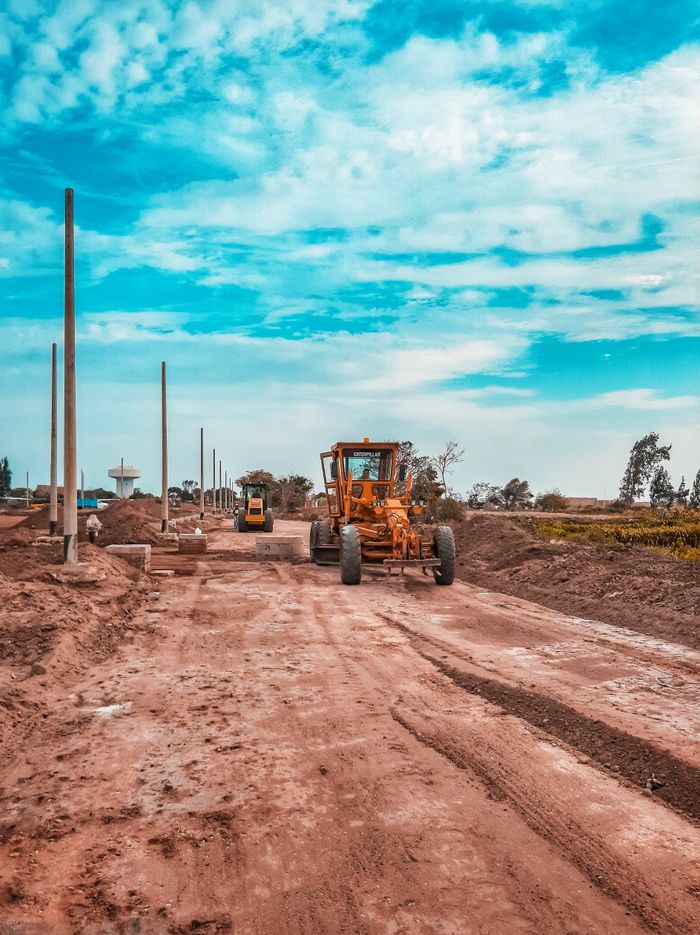 Home 8 Yellow bulldozer working on a dirt road under a blue sky, ideal for construction themes.